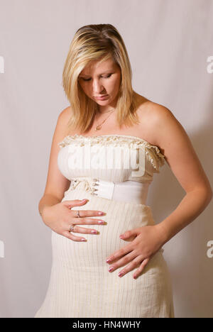 schöne blonde behaarte junge Frau schwanger im weißen Kleid Stockfoto