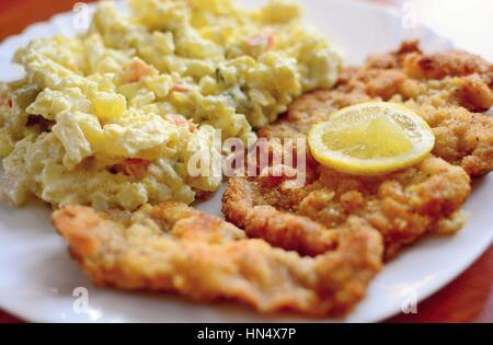 Traditionelle gebratenes Schweinefleisch Schnitzel mit tschechischen Kartoffel-Mayonnaise Salat und Zitrone Scheibe obenauf. Stockfoto