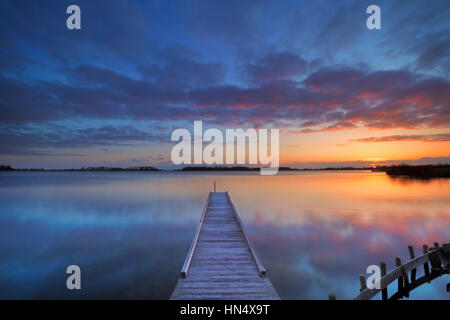 Ein kleiner Steg an einem See bei Sonnenaufgang. Fotografiert in der Nähe von Amsterdam in den Niederlanden. Stockfoto