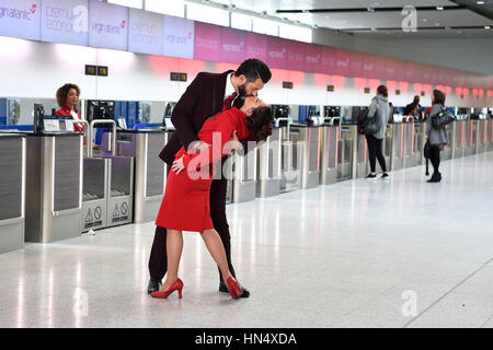 Gary Ogden, Flight Service Manager, und seine Frau Jessie Ogden, Cabin Service Supervisor, stellen das ikonische V-J Day Kiss-Foto im neuen Check-in-Bereich am Nordterminal des Flughafens Gatwick nach, um den neuen Kiss&Fly-Service von Virgin Atlantic zu starten. Das ermöglicht Paaren eine Stunde kostenloses Parken für Abschiedsmomente am Flughafen in West Sussex. Stockfoto