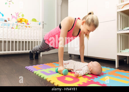 Mutter Fitness zu tun und mit ihrem Baby spielen Stockfoto