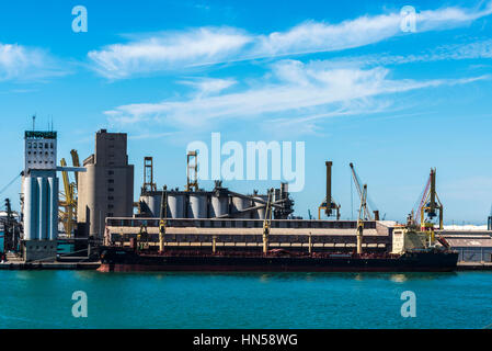 Barcelona, Spanien - 21. Juni 2016: Frachtschiff vor Anker vor einem Silo im Hafen von Barcelona, Katalonien, Spanien Stockfoto