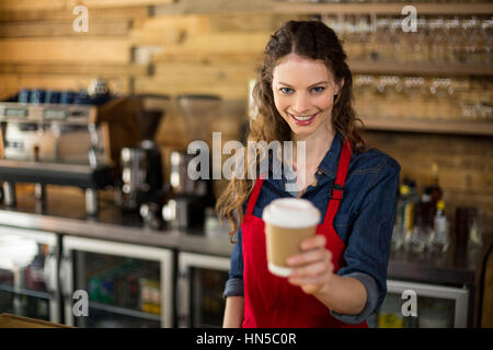 Porträt von lächelnden Kellnerin serviert eine Tasse Kaffee an Kunden in CafÃƒÂ © Stockfoto