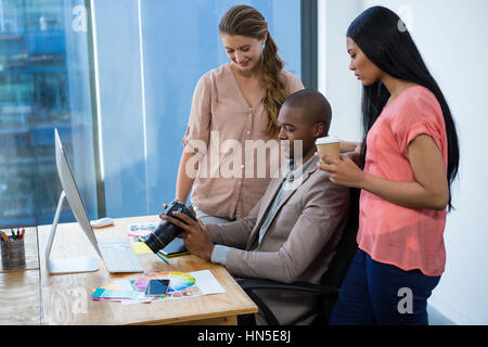 Grafiker, die Überprüfung der Fotos in der Kamera mit Kollegen im Büro Stockfoto