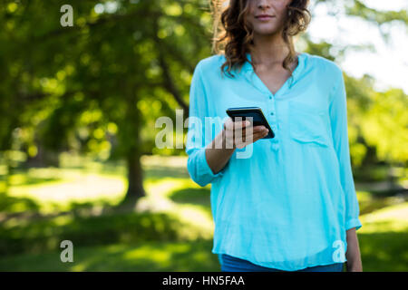 Mittleren Bereich der Frau mit Handy im park Stockfoto