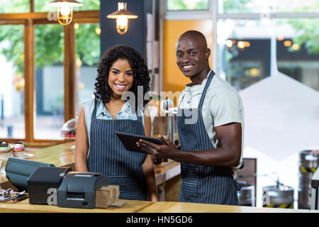 Porträt von lächelnden Kellner und Kellnerin mit digital-Tablette am Schalter im café Stockfoto