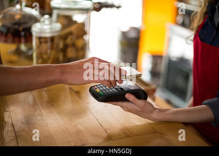 Mann, die Zahlung der Rechnung durch Smartphone mit NFC-Technologie im café Stockfoto