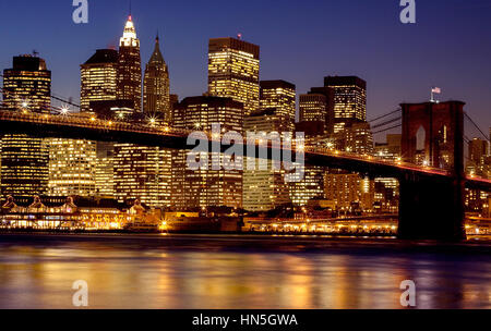 Eine Nachtaufnahme einer beleuchteten Brooklyn Brücke mit einer hellen Manhatan Skyline in der Abenddämmerung aus Brooklyn Bridge Park genommen Stockfoto