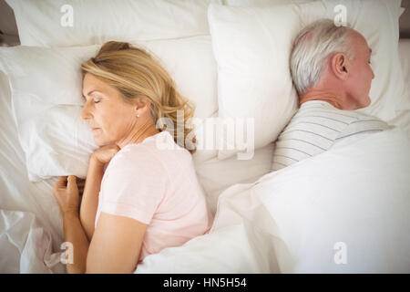 Älteres paar Rücken an Rücken auf dem Bett im Schlafzimmer schlafen Stockfoto