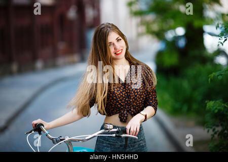 Mädchen steht auf der Straße mit dem Fahrrad und lächelnd Stockfoto