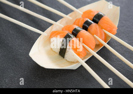 Nahaufnahme von Sushi auf Boot geformte Platte mit Stäbchen Stockfoto