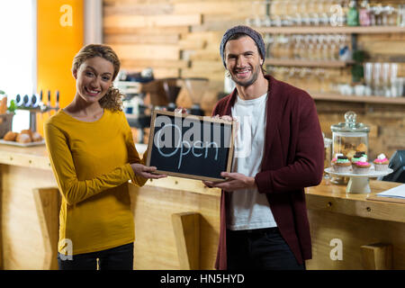 Porträt des Lächelns Besitzer stehend mit Schild "geöffnet" Board im café Stockfoto