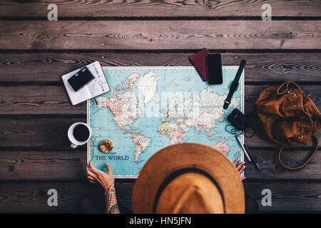 Junge Frau Urlaubsplanung mit Karte und Kompass zusammen mit anderen Reise-Accessoires. Touristischen braunen Hut, Blick auf die Weltkarte. Stockfoto
