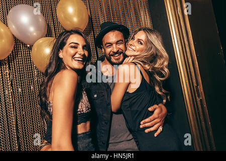 Porträt von gut aussehender Mann mit Freundinnen in Disco. Junge Freunde auf einer Party im Nachtclub. Stockfoto