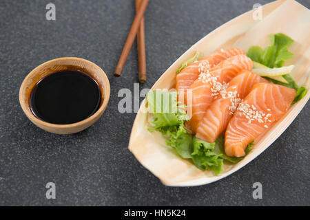 Sushi auf Boot geformte Platte mit Stäbchen und sauce Stockfoto