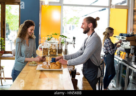 Kellner mit einer Tasse Kaffee an Kunden am Schalter im CafÃƒÂ © Stockfoto