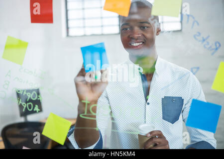 Lächelnd Geschäftsmann auf Haftnotizen im Büro schreiben Stockfoto