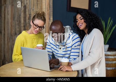 Glückliche Freunde mit Laptop beim Kaffeetrinken in CafÃƒÂ © Stockfoto