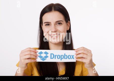 Kiew, UKRAINE - 22. August 2016: Frau Hände mit Dropbox-Logo-Schild auf Papier auf weißem Hintergrund gedruckt. Dropbox-Cloud-Speicher, so dass Anwender ihre Daten auf Servern in der Cloud speichern. Stockfoto