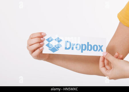 Kiew, UKRAINE - 22. August 2016: Frau Hände mit Dropbox-Logo-Schild auf Papier auf weißem Hintergrund gedruckt. Dropbox-Cloud-Speicher, so dass Anwender ihre Daten auf Servern in der Cloud speichern. Stockfoto