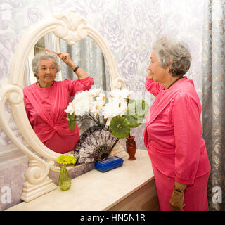 Alte Frau im Schlafzimmer in der Nähe von Spiegel Stockfoto