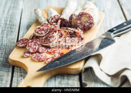 Lecker in Scheiben geschnittene Salami auf Schneidebrett. Stockfoto