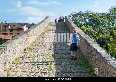 Frau Tourist geht über die römische Brücke von Cangas de Onis eine alte über den Fluss Sella in den Picos de Europa-Spanien Steinbrücke Stockfoto