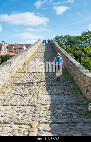 Frau Tourist geht über die römische Brücke von Cangas de Onis eine alte über den Fluss Sella in den Picos de Europa-Spanien Steinbrücke Stockfoto