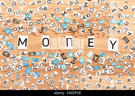 Geld das Wort Ausschneiden von Buchstaben auf Holztisch Stockfoto