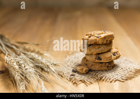 Schokoladen-Plätzchen auf meschotschek Tuch auf Holz. Chocolate Chip Cookies und Reis Malz erschossen auf einem braunen Tuch. Stockfoto