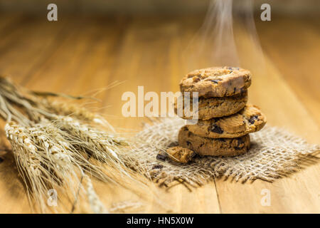 Schokoladen-Plätzchen auf meschotschek Tuch auf Holz. Chocolate Chip Cookies und Reis Malz erschossen auf einem braunen Tuch. Stockfoto