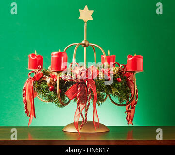 Vintage Adventskranz mit vier brennende rote Kerzen und Goldstern auf grünem Hintergrund, Beleuchtung und Dekoration für die Weihnachtszeit Stockfoto