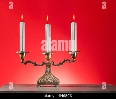 Antik Bronze Kerzenständer mit drei brennende silberne Kerzen auf Fäulnis Hintergrund Stockfoto