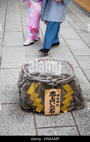 KYOTO, JAPAN - 24. März 2012: Eine "Liebe Stein" am Schrein Jishu mit traditionell gekleideten paar im Hintergrund. Finden Sie Ihren Weg zwischen Stein Stockfoto