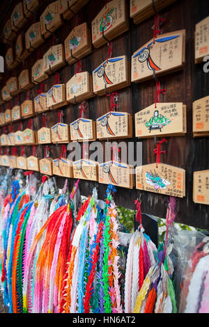 Kyoto, Japan - 18. März 2012: Nahaufnahme von Gebet Tabletten und Ketten von Origami Kraniche aus Papier hängen an einem Shinto-Schrein. Die kleinen Holztafeln, cal Stockfoto