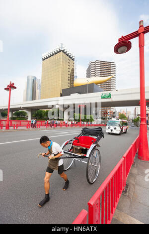 Tokyo, Japan - 26. Mai 2012: Ein Mann zieht eine leere Rikscha Azuma Brücke in Tokios Asakusa Bezirk mit gold farbigen Asahi-Gebäude Stockfoto