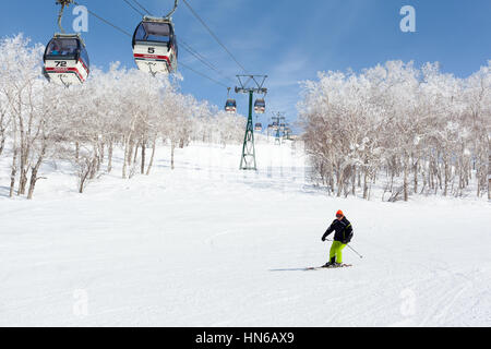 NISEKO, JAPAN - März 9: Ein Mann fährt vorbei an eine Gondelbahn in das Skigebiet von Niseko Annupuri am 9. März 2012. Niseko ist ein großes Skigebiet befindet sich auf Stockfoto