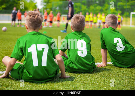 Kinder-Fußball-Spieler auf dem Platz sitzen. Jungen Fußball-Nationalmannschaft auf dem grünen Rasen sitzen. Stockfoto