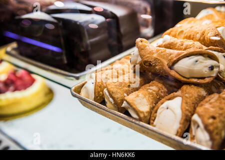 Cannoli und Scheiben Kuchen Dessert Display hinter Glas in einem Geschäft Stockfoto