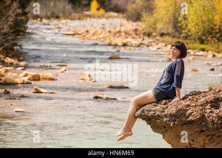 Weiß Mineral Creek Wasserstrom in Colorado, USA im Herbst mit goldenen Espen und Frau am Rand, die Füße im Wasser eintauchen Stockfoto