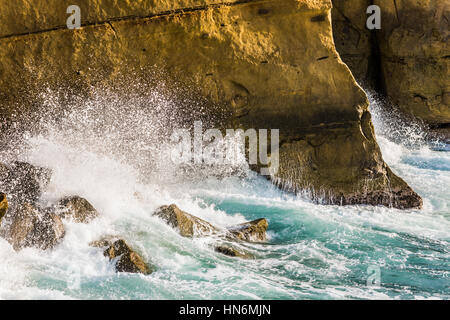 Welle stürzt ab und Spritzen Wassertropfen auf orange sunset Cliffs in San Diego Stockfoto