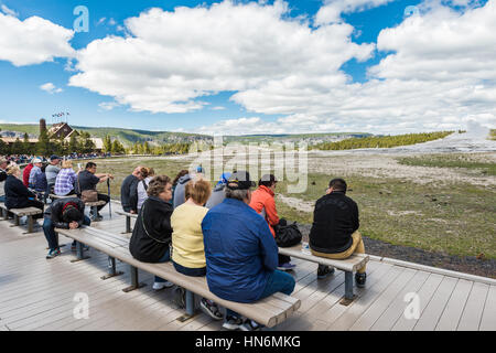 Yellowstone-Nationalpark, USA - 17. Mai 2016: Müde Touristen sitzen auf Bänken und warten auf den Ausbruch des Old Faithful Geysir Stockfoto