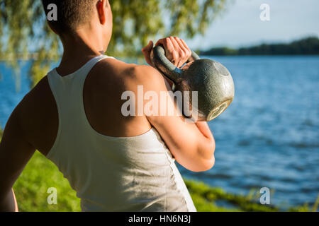 Nahaufnahme von Fit muskulöser Mann mit schweren Kettlebell vor Fluss im park Stockfoto