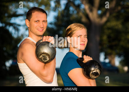 Mann und Frau Paar halten schwere Kettlebell Gewichte im Outdoorpark Stockfoto