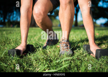 Nahaufnahme von Fit Jüngling mit Hanteln auf dem Rasen Stockfoto