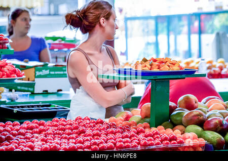 Montreal, Kanada - 26. Juli 2014: Frau Aushändigung Proben von Obst auf Jean-Talon Farmers Market in der Innenstadt mit Obst-displays Stockfoto