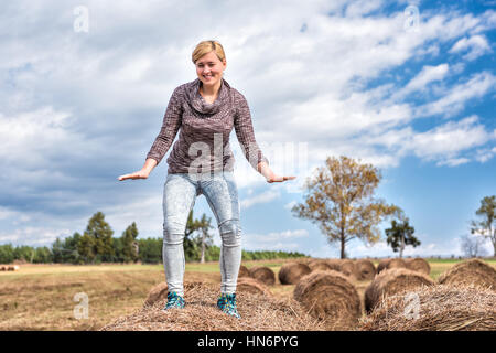 Junge Frau balancieren auf Heuballen roll Stockfoto