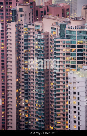 Detailansicht der Skyskraper in einer dicht besiedelten Stadt. Hochhäuser mit Wohnblocks in der Nacht. Hongkong, China Stockfoto