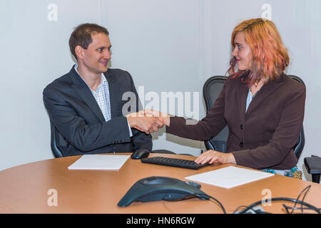 Young Business-Frau und Mann Händeschütteln am Tisch und lächelt Stockfoto
