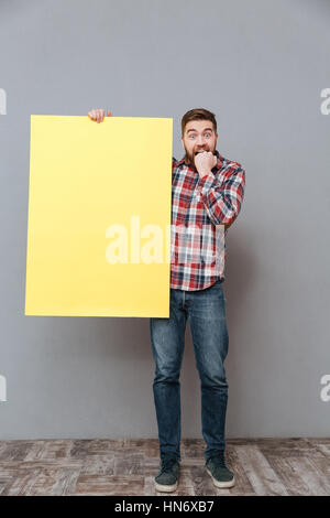 Voller Länge Bild der Angst Mann im Hemd, die leere Kammer im Studio und Blick in die Kamera halten. Isolierte grauen Hintergrund Stockfoto